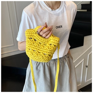 Detail of hand-woven bright yellow bucket bag with hollow knit pattern and crochet strap