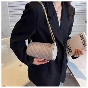 Détail du sac cylindre matelassé avec bandoulière en chaîne dorée et texture cuir