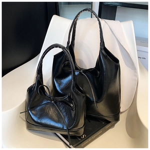 Detail showing two sizes of black oil wax leather tote bags with elegant bow accents