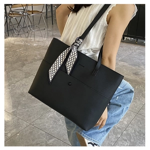 Close-up of black pebble leather tote bag featuring a checkered silk scarf on the strap