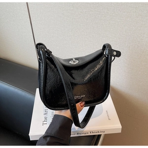 Detail of black glossy crinkle texture crossbody bag with silver twist lock and strap