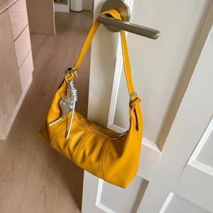Detailed macro view of orange hobo bag with grainy leather texture and heart charm