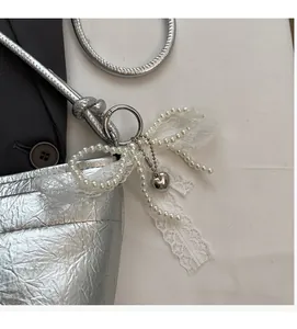 Close-up of metallic silver bucket bag featuring pearl lace bow and heart charm