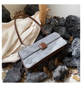 Détail du motif paysager gris gaufré sur le sac à bandoulière avec finitions en cuir brun