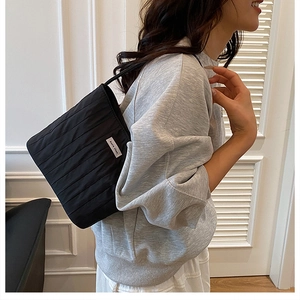 Detail of black quilted shoulder bag featuring dense pleats and Ann's then brand label