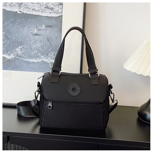 Detailed shot of a black nylon crossbody bag featuring a circular logo and front zipper pocket
