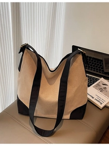 Large beige canvas tote bag with black strap accents and minimalist slouchy silhouette