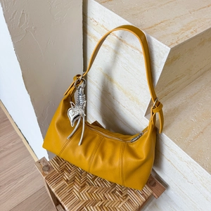 Close-up of yellow hobo bag with lychee texture and silver heart butterfly charms