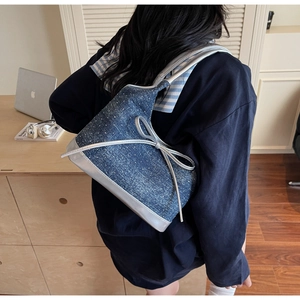 Detail of denim shoulder bag featuring silver leather bow and sparkling star rhinestones