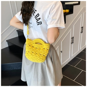 Detail of bright yellow hand-knitted crossbody bucket bag with hollow woven texture