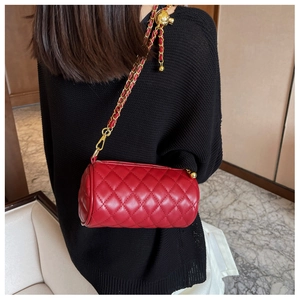 Vue détaillée du sac cylindrique rouge matelassé avec chaîne dorée et bille réglable