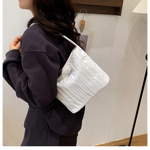 Detail of white pleated tote bag with thin shoulder strap on a model shoulder