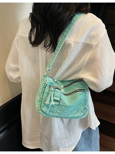 Mint green denim crossbody bag with vintage pockets shown on a model against stairs