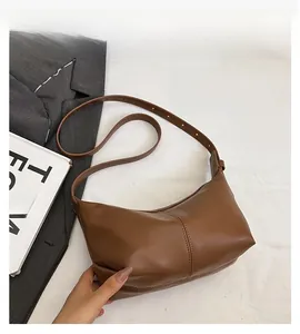 Close-up of brown leather hobo bag showing retro matte finish and vertical stitching detail