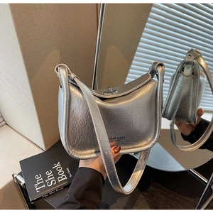 Close-up of silver textured handbag with metallic finish and metal twist-lock buckle
