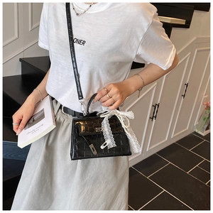 Detail of black crocodile texture handbag featuring lace and pearl bow decoration