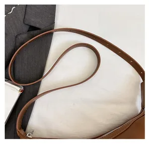 Detail of adjustable slender strap and silver zipper on the brown leather hobo shoulder bag