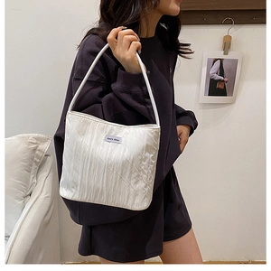 Detail of white pleated canvas shoulder bag with satin texture and Anna's then brand label