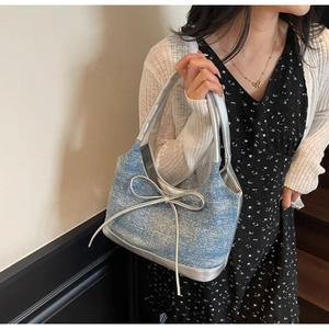 Detail of light blue denim tote bag with silver bow decoration and metallic trim