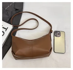 Brown leather moon bag shown with smartphone to demonstrate interior storage capacity