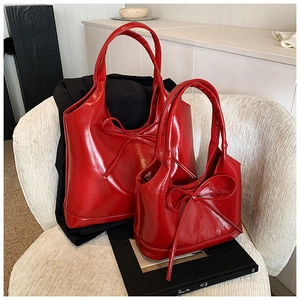 Detail of red bow knot tote bags with shiny patent leather finish on white velvet chair