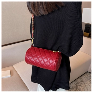 Gros plan d'un sac cylindrique matelassé rouge avec bandoulière chaîne dorée tissée