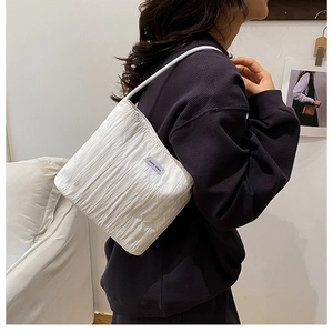 Detail of white pleated canvas bucket bag featuring a soft fabric texture and logo label