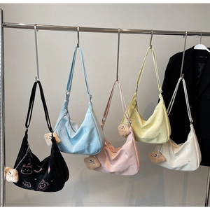 Row of colorful nylon crescent bags with cat embroidery and plush charms on hangers