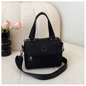 Detail of waterproof black nylon bag featuring circular logo and adjustable wide shoulder strap