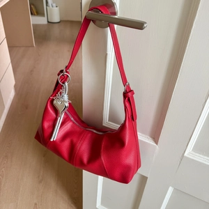 Detail of red pebbled leather hobo bag with silver heart charm and zipper tassel
