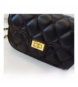 Close-up of golden metal turn-lock and diamond quilted stitching on a black shoulder bag