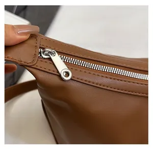 Detailed macro view of the smooth silver metal zipper on a brown leather dumpling bag