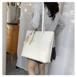 Detail of creamy white tote bag featuring lychee grain leather and silk scarf handle