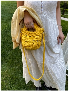 Detailed close-up of yellow crochet bucket bag showing hand-knitted hollow pattern