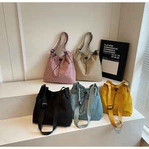 Multiple colors of drawstring nylon tote bags displayed on a clean minimalist stand