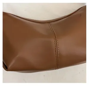 Detailed macro view showing vertical double stitching and caramel leather texture on a tote