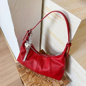 Close-up of red lychee leather hobo bag with silver heart and sword metal charms