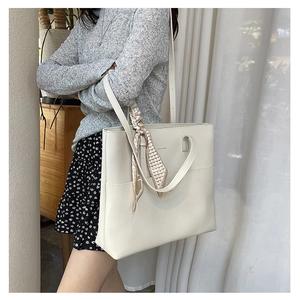 Detail of off-white lychee grain tote bag with elegant geometric silk scarf on handle