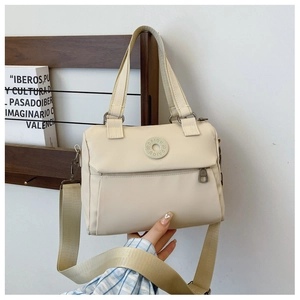 Detail of beige nylon crossbody bag featuring round embossed logo and adjustable strap
