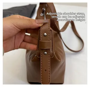Detail of adjustable leather strap with metal buckle for brown crossbody dumpling bag