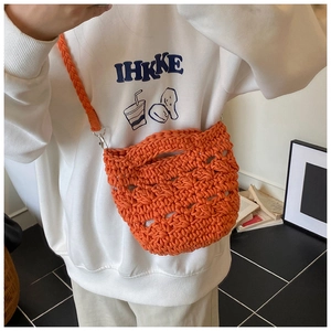 Close-up of handmade orange crochet bucket bag with hollow mesh texture and woven strap