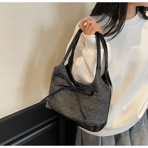 Detail view of denim tote bag with polka dots and a large black bow on a model