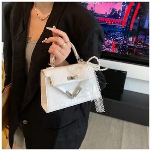 Detail of white crocodile pattern Kelly bag with pearl handle and lace bow decoration