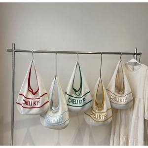 Detail of five colorful woven crochet hobo tote bags hanging on a metal rack