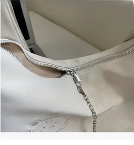 Detail of smooth silver zipper and Meilaidi embroidery on cream crossbody bag