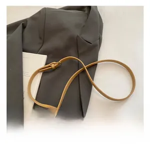 Detail view of adjustable leather bag strap in tan brown with a cute plush bear pendant