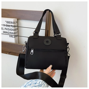 Detail of black nylon crossbody bag with wide strap and front zipper pocket close-up