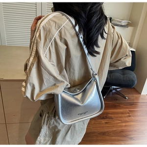 Detail of silver metallic leather crossbody bag featuring a swivel lock and printed logo