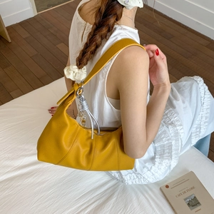 Detail of a mustard yellow hobo bag in lychee pattern leather with silver zipper closure