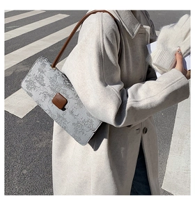 Détail d'un élégant sac à bandoulière rectangulaire avec motif vintage sur tissu gris
